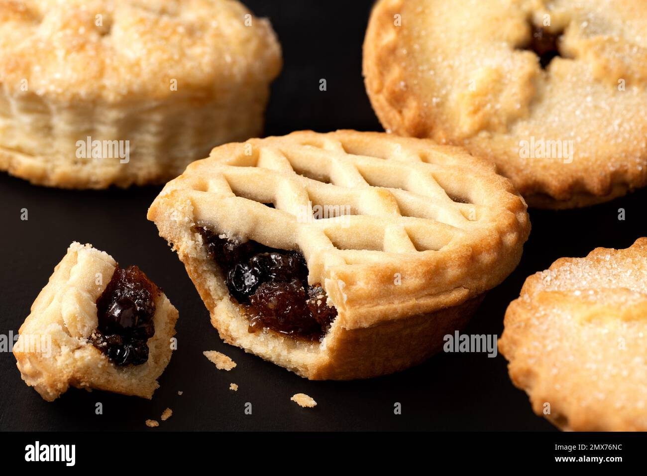 Tutte le torte tritate di burro sulla superficie nera. Uno rotto con ripieno di frutta visibile. Foto Stock