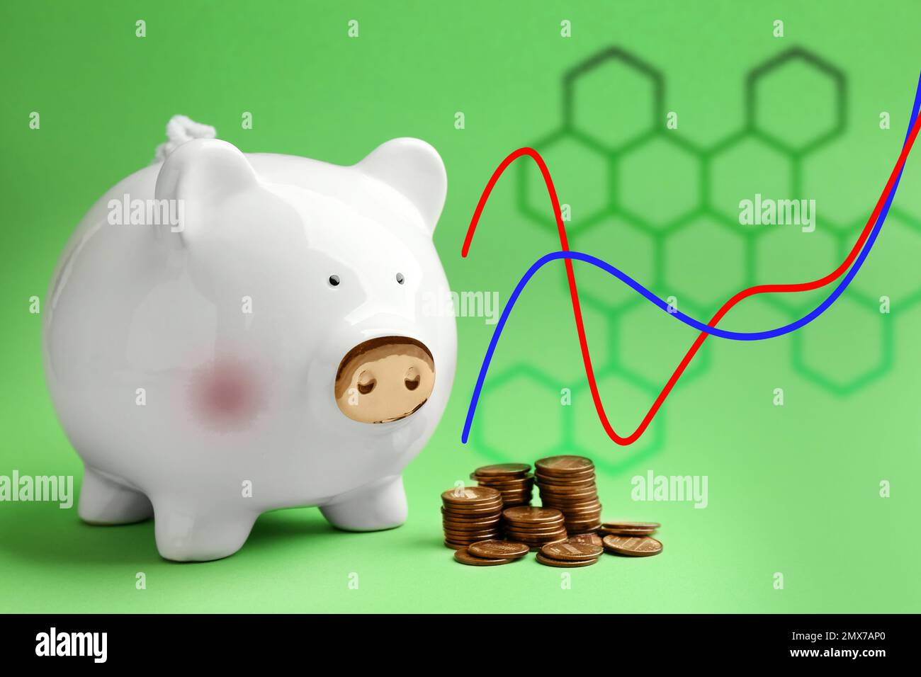 Banca di piggy bianco con monete e grafico su sfondo verde Foto Stock