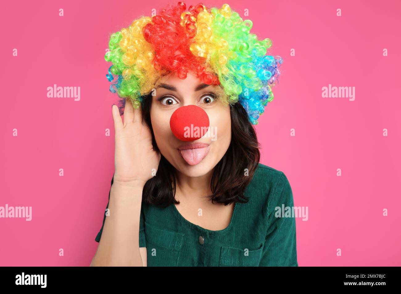Donna divertente con parrucca arcobaleno e naso clown su sfondo rosa. Aprile Fool's Day Foto Stock