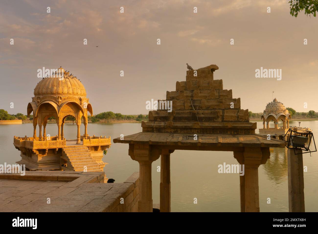 Chhatris e santuari di divinità indù e divinità al lago Gadisar, Jaisalmer, Rajasthan, India. Architettura indoislamica , tramonto e nuvole colorate Foto Stock