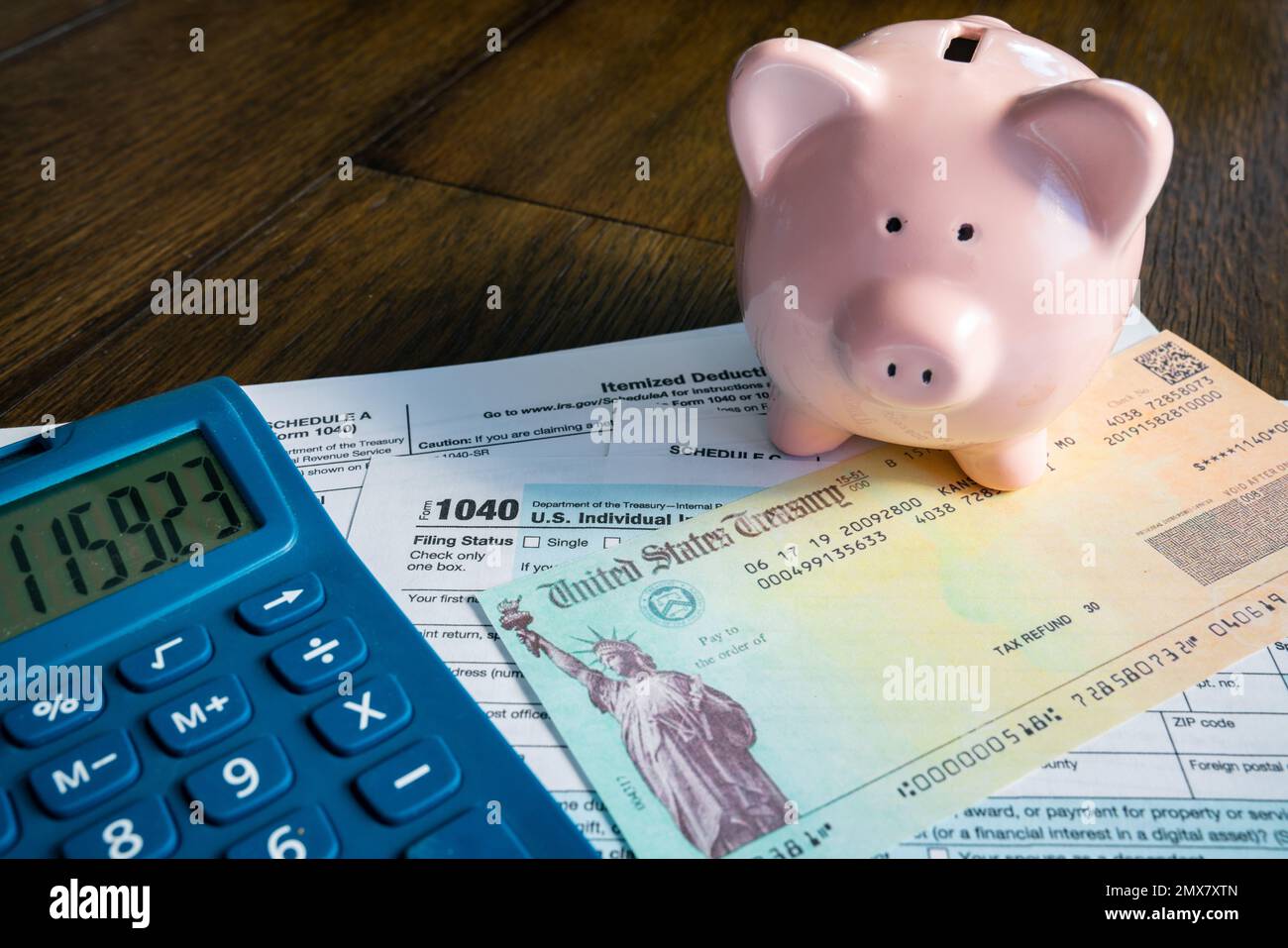 Controllo rimborso tasse con banca rosa piggy e calcolatrice Foto Stock
