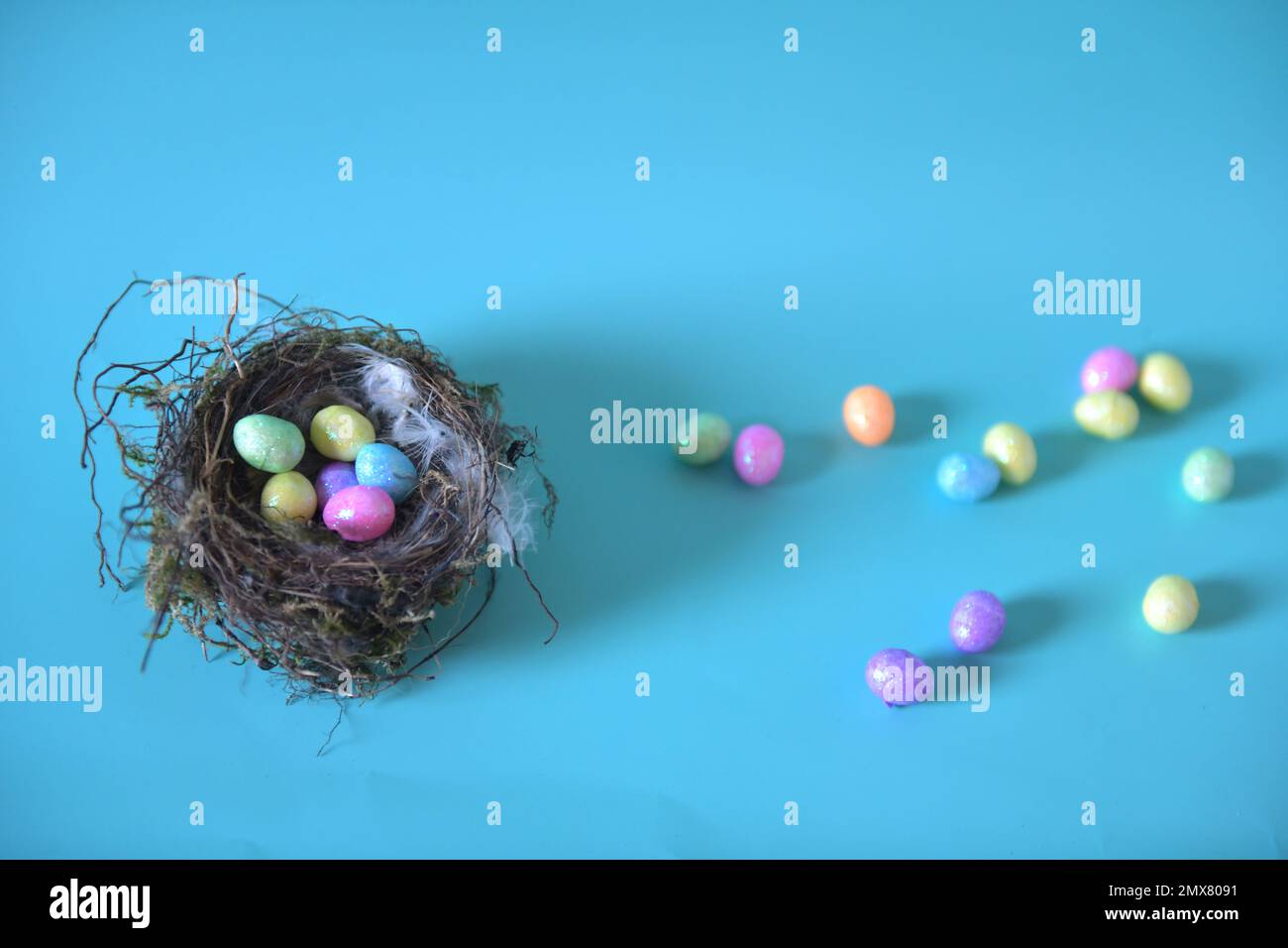 Foto orizzontale con spazio di copia del nido d'uccello con piccole uova di Pasqua colorate. Alcune uova si sono sparse sul tavolo e sullo sfondo. Foto Stock