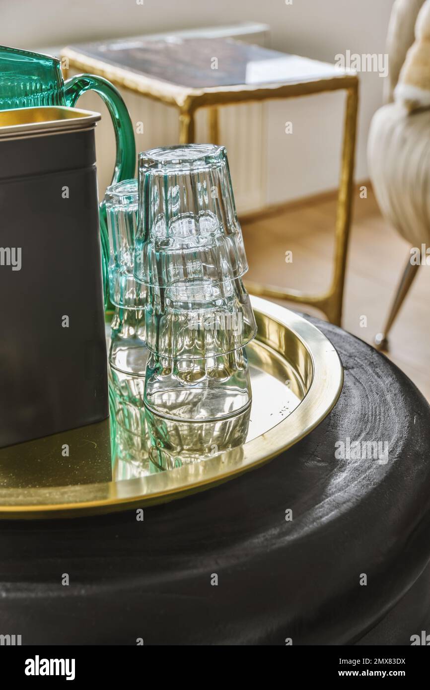 Vassoio in metallo con bicchieri vicino alla caraffa con acqua e vasetto sul tavolo Foto Stock