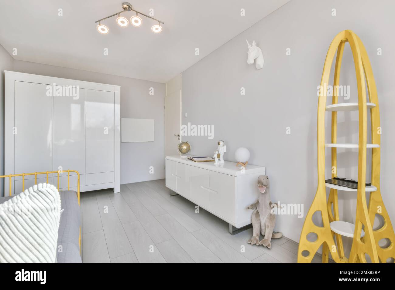 Design contemporaneo minimalista delle camere da letto per bambini arredate con guardaroba bianco e mensole vicino al letto con libreria gialla e giocattoli Foto Stock