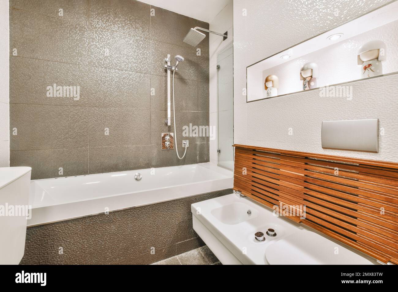 Bagno dal design contemporaneo con vasca e doccia vicino al lavabo decorato  con elementi in legno in appartamento luminoso Foto stock - Alamy