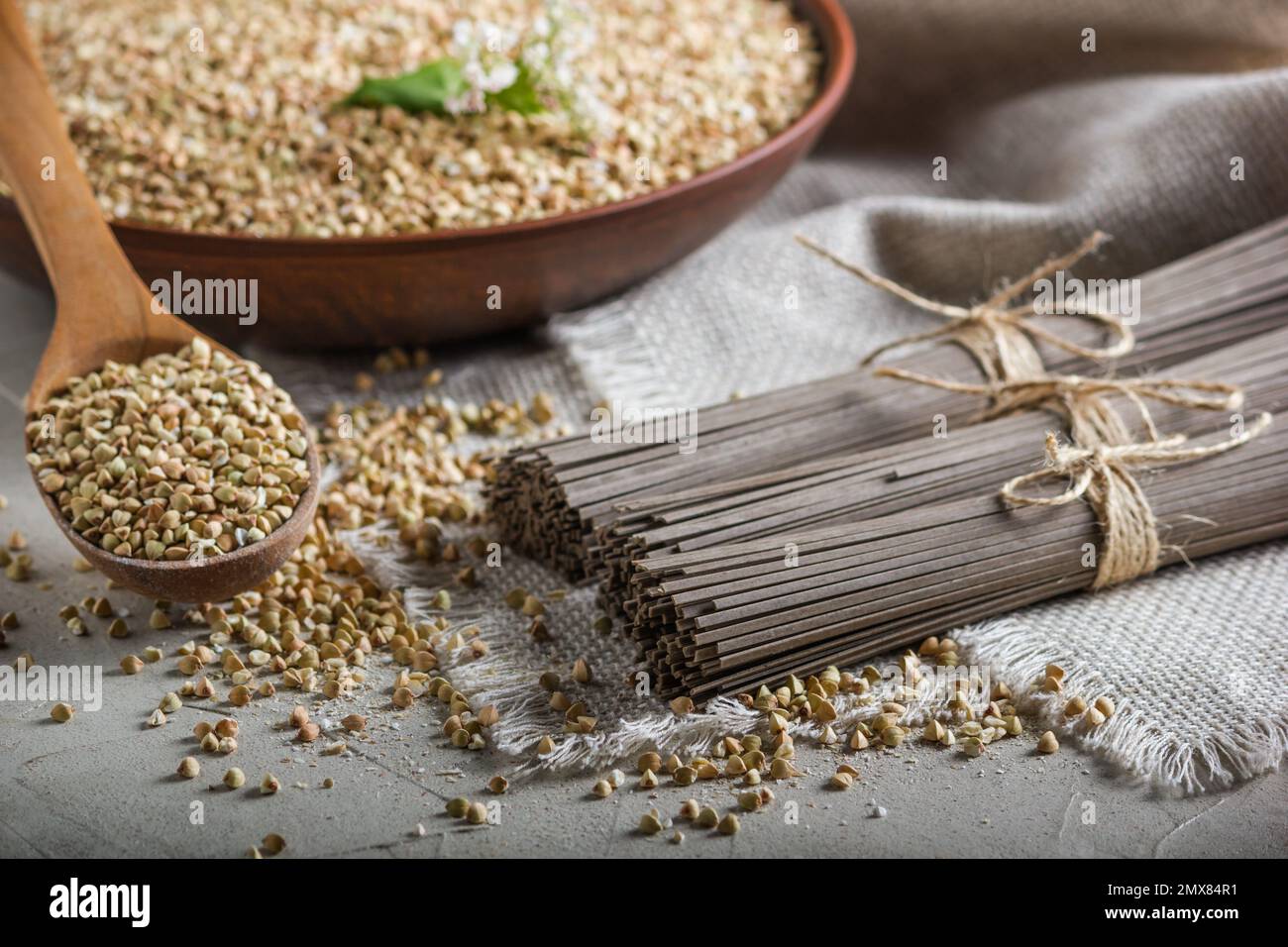 Natura morta rurale - noodle tradizionali giapponesi di soba fatte di farina di grano saraceno e le semole pelate di grano saraceno, sullo sfondo di burlap, closeup Foto Stock