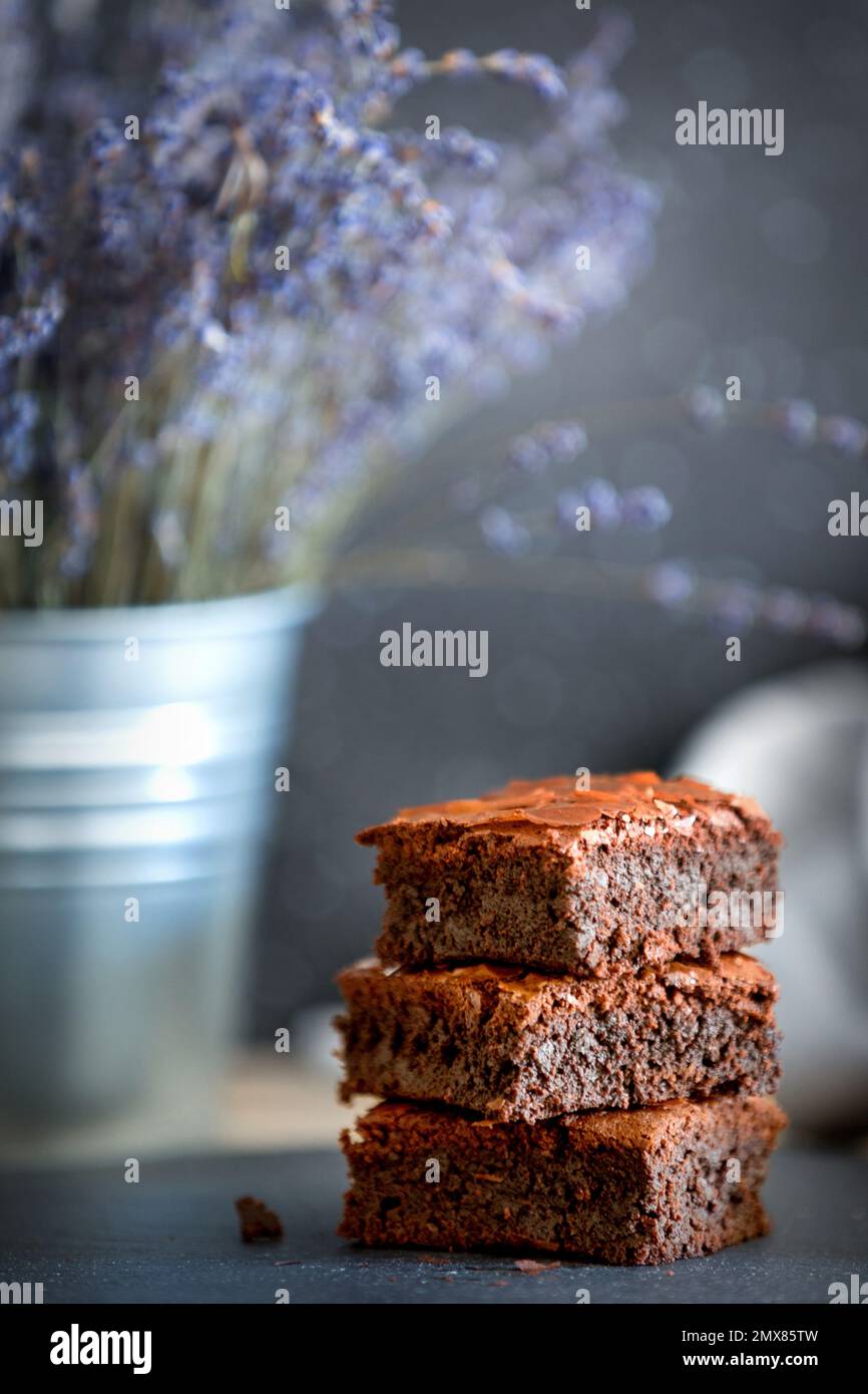 Torta di brownie al cioccolato fondente fatta in casa impilata su un piatto di pietra con spazio per le copie. Fiori di lavanda sfondo Foto Stock