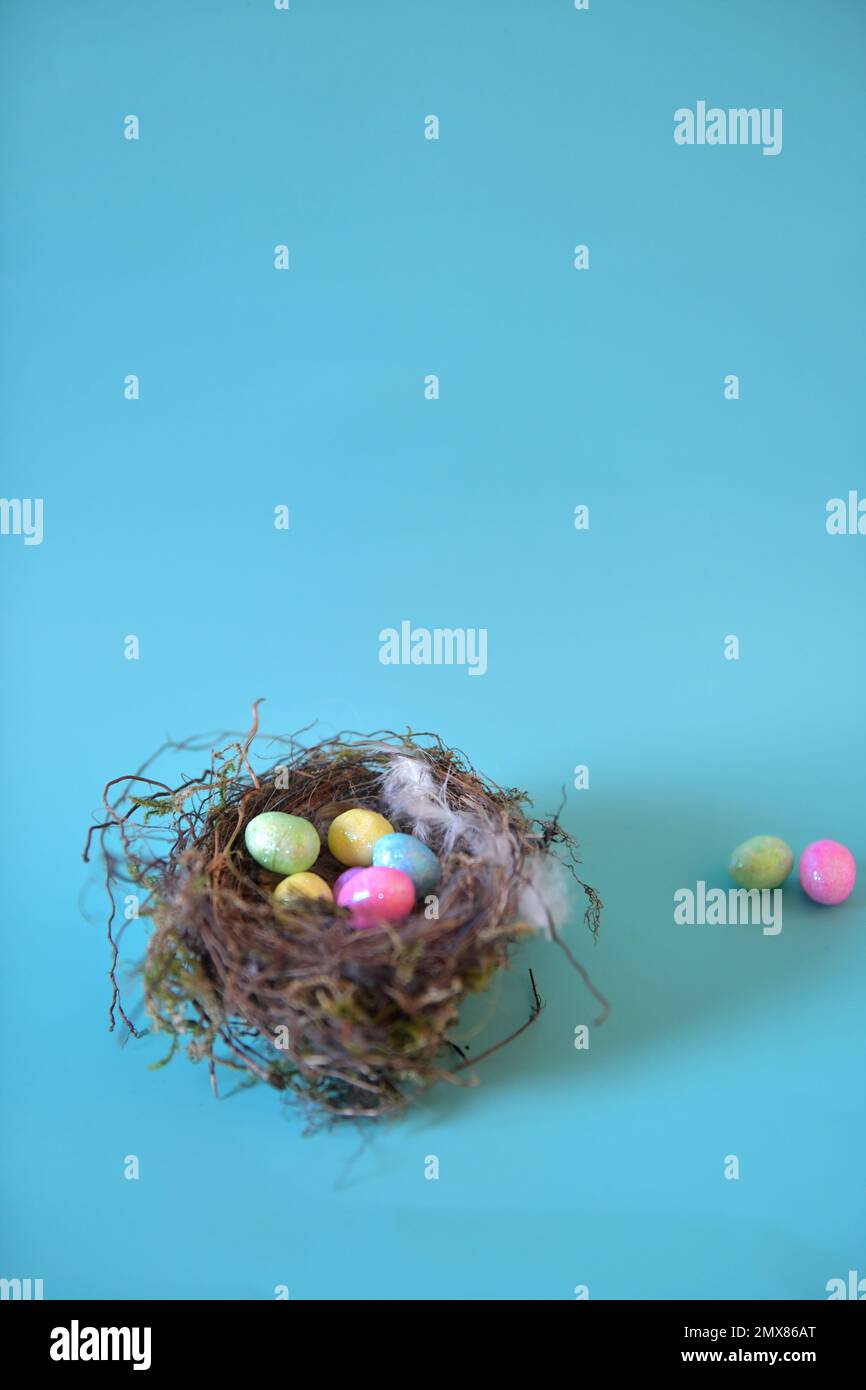 Ripresa verticale del nido d'uccello su sfondo turchese. Uova di Pasqua artificiali e spazio di copia nella metà superiore della foto. Foto Stock