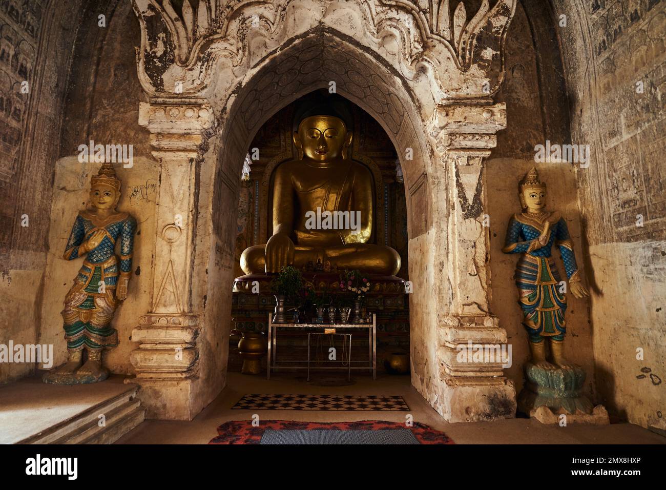 Una grande statua dorata del Buddha seduta in un antico tempio a Bagan, Myanmar (Birmania). Foto Stock