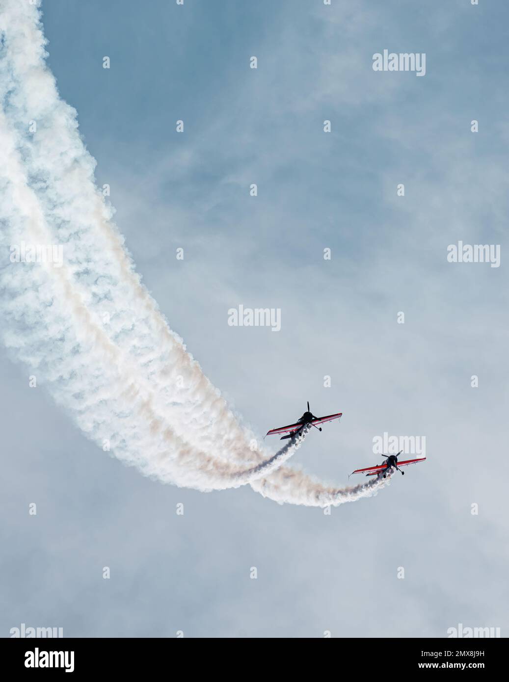 due piccoli piani volano paralleli in una traiettoria verso l'alto sopra il cielo blu. tracce di condensa e nuvole. concetto di amicizia e lealtà. Sostegno reciproco Foto Stock