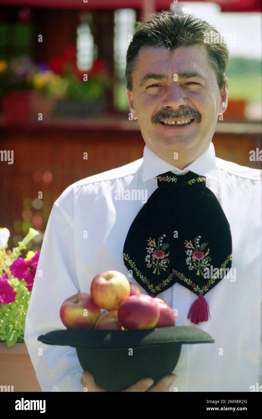 Contea di Sibiu, Romania, circa 2000. Uomo locale della comunità sassone in abiti tradizionali, in posa con un cappello pieno di mele. Foto Stock
