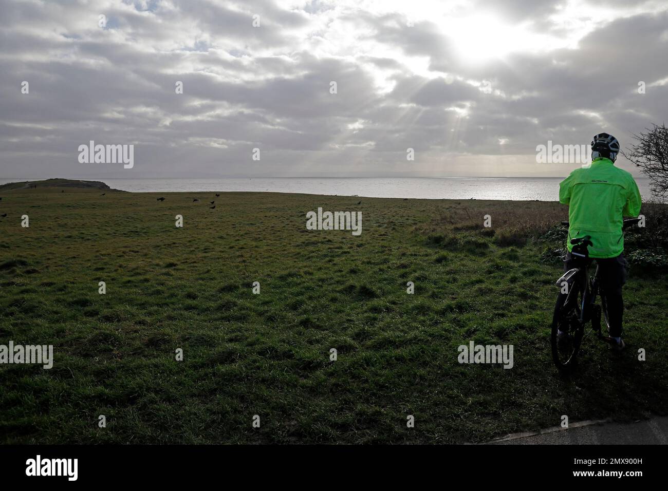 Ciclista guardando la vista, Barry Island headland, Little Island verso Friar's Point in lontananza. Gennaio 2023. Inverno. Foto Stock