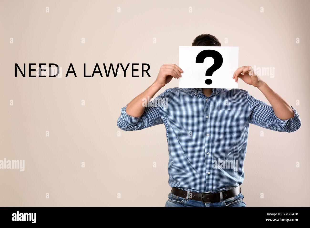 Uomo che tiene carta con punto interrogativo e testo BISOGNO Di Un AVVOCATO? su sfondo beige Foto Stock