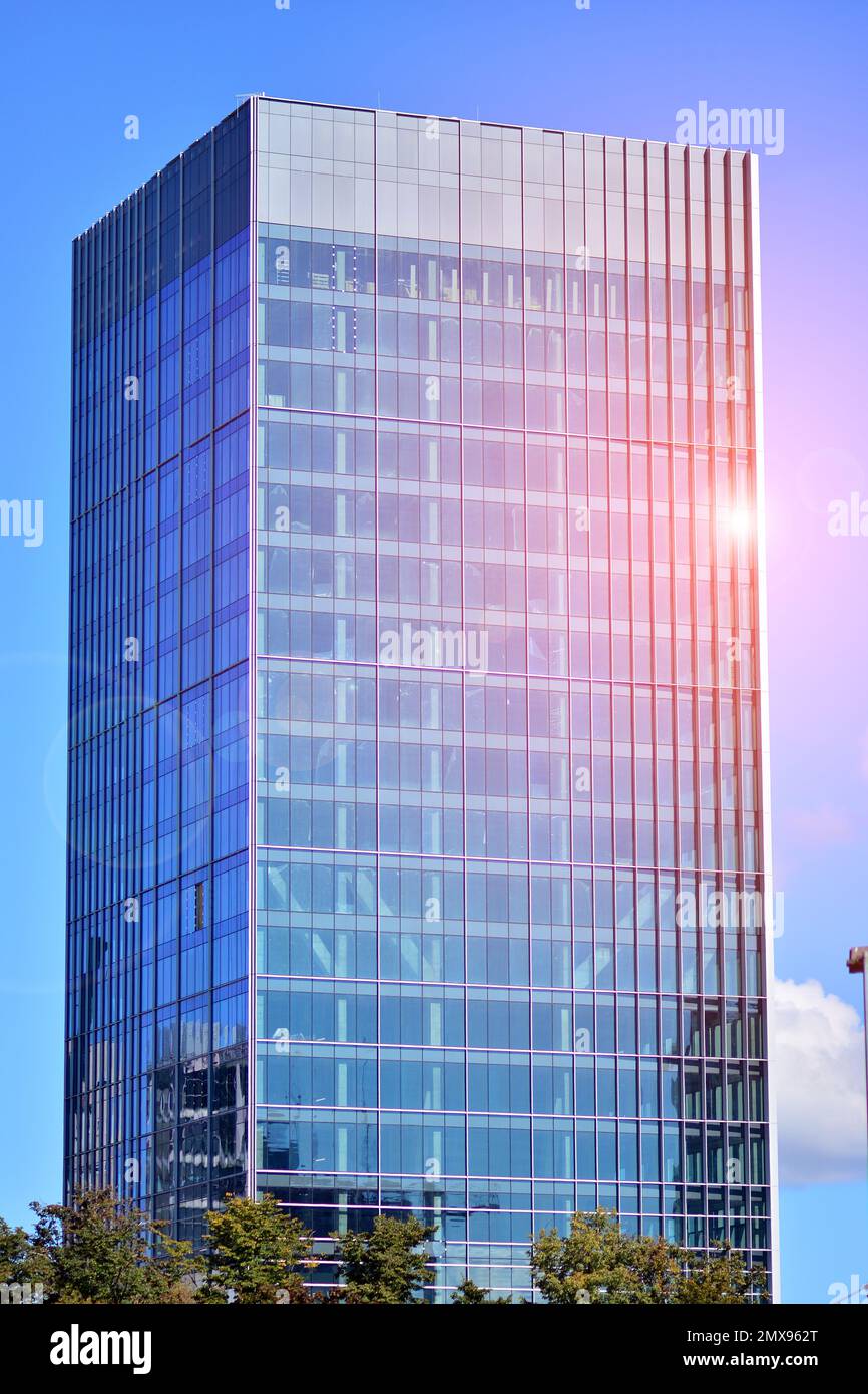 Moderna facciata in vetro contro il cielo blu. Vista dal basso di un edificio nel quartiere degli affari. Vista ad angolo basso della facciata di vetro di un edificio di uffici. Foto Stock