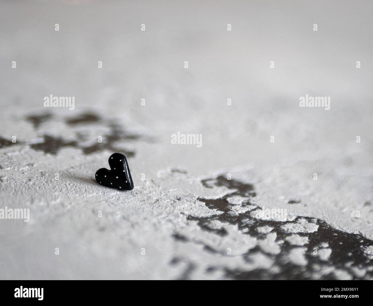 Cuore nero su uno sfondo concreto, fuoco selettivo. Concetto di morbilità, dolore, ansia, amore non rifatto, affetto Foto Stock