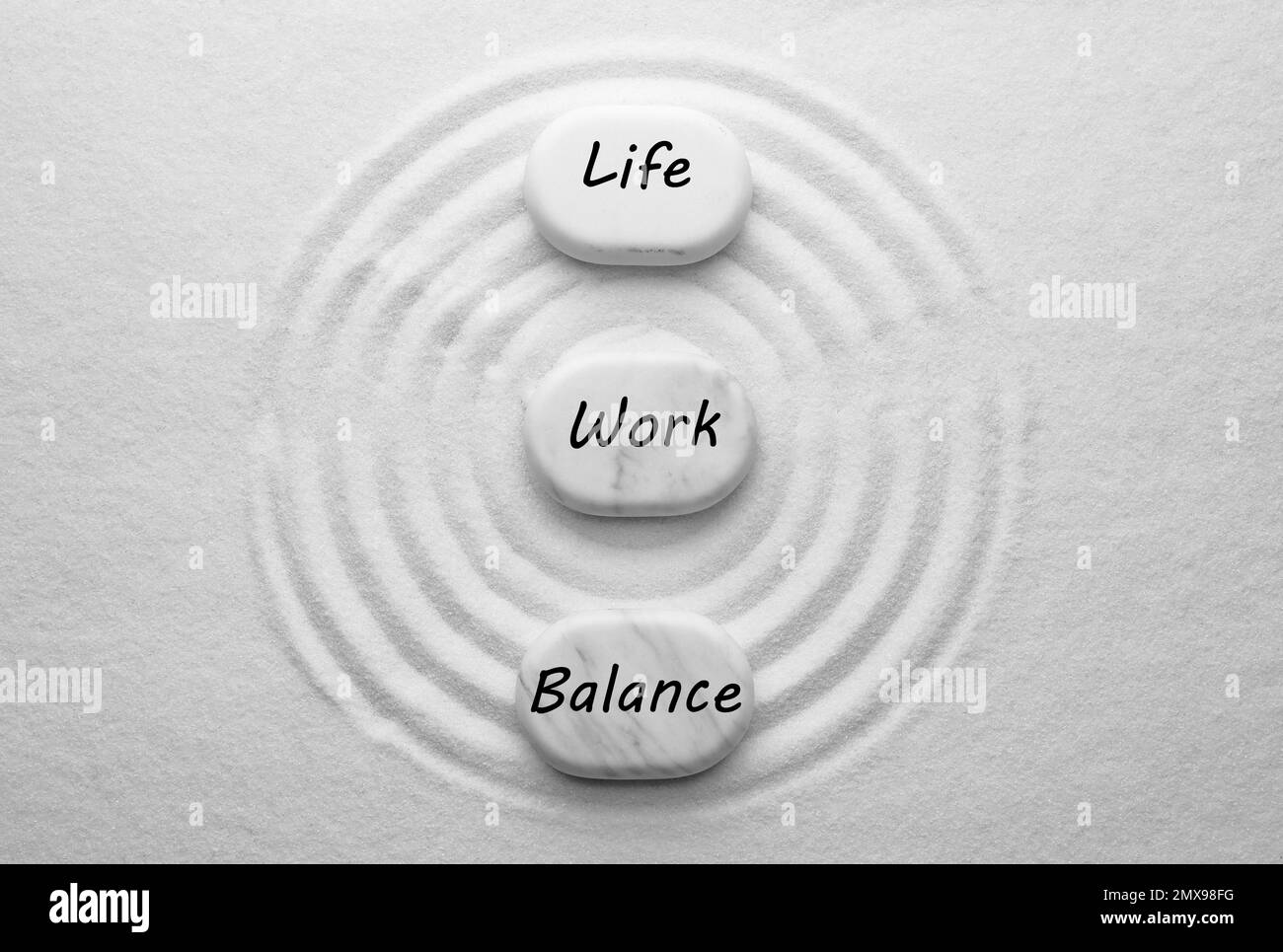 Concetto di equilibrio tra vita lavorativa e vita privata. Pietre su sabbia con disegno, giacitura piatta Foto Stock