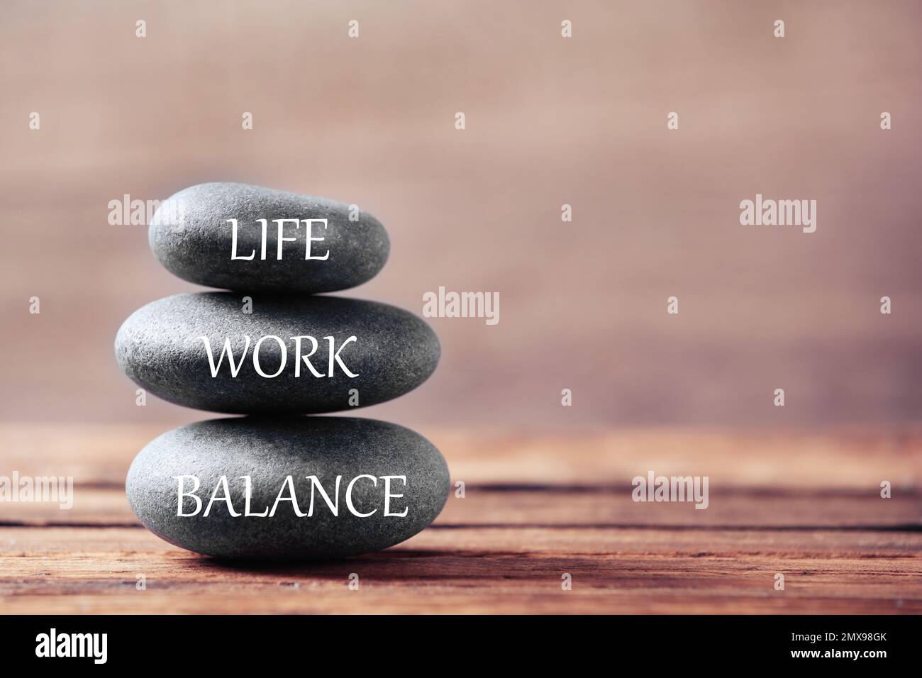 Concetto di equilibrio tra vita lavorativa e vita privata. Pietre impilate su tavolo di legno, spazio per il testo Foto Stock