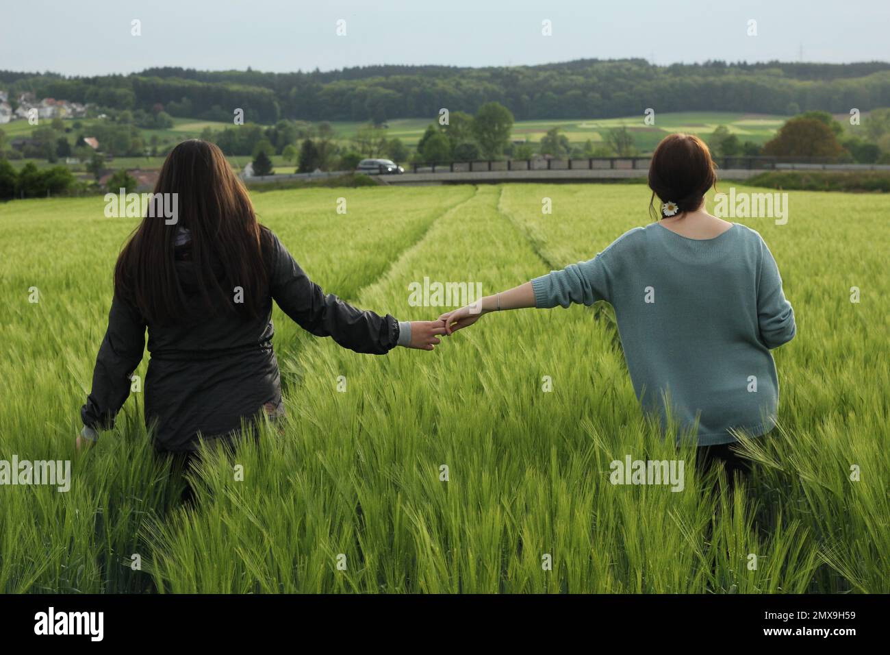 Due donne che attraversano il campo di mais e tengono le mani Foto Stock