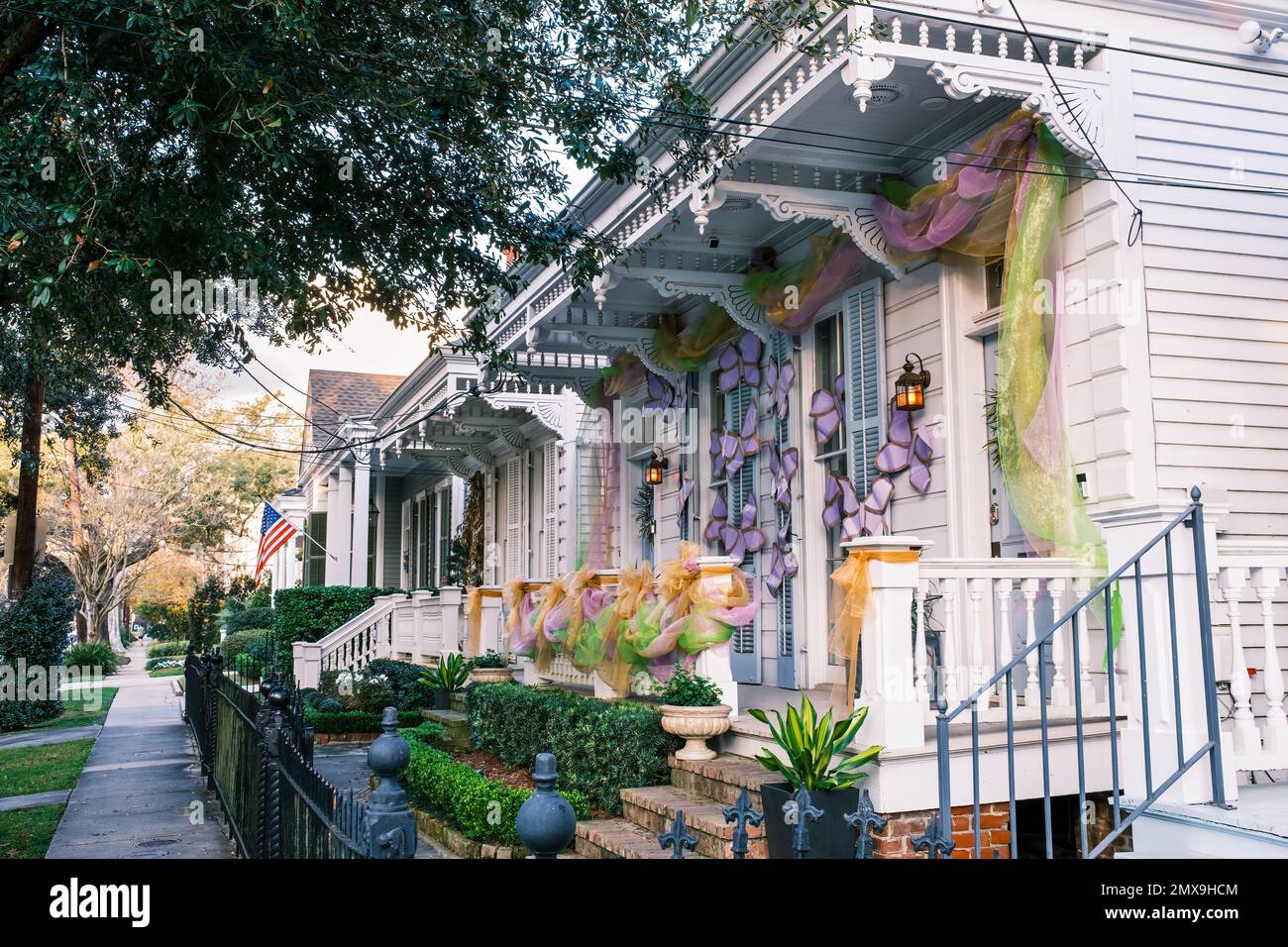 NEW ORLEANS, LA, USA - 31 GENNAIO 2023: Fila di storiche case doppie con fucili a canna con decorazioni Mardi Gras nel quartiere Uptown Foto Stock