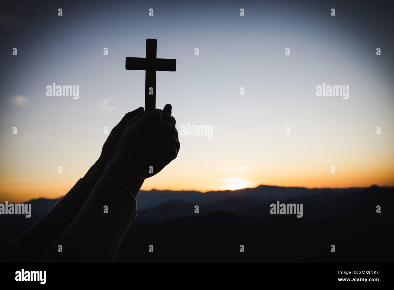 Silhouette di donna cristiana che prega a mano, donna che tiene un crocifisso che prega, spiritualità e religione, donna che prega a dio. Concetto di Cristianesimo. Foto Stock