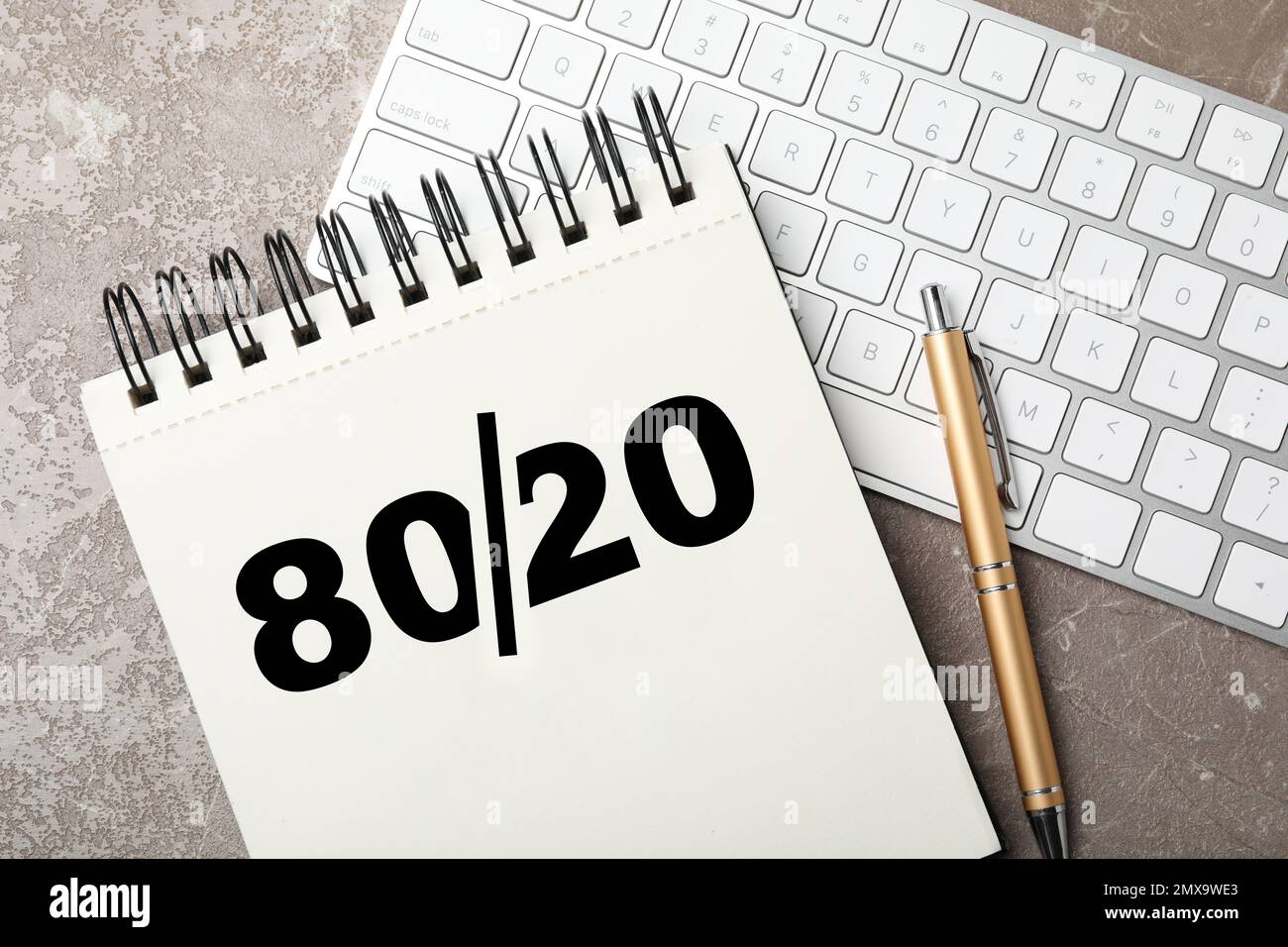 Principio di Pareto. Notebook con rappresentazione a 80/20 regole, penna e tastiera su sfondo grigio, piatto Foto Stock