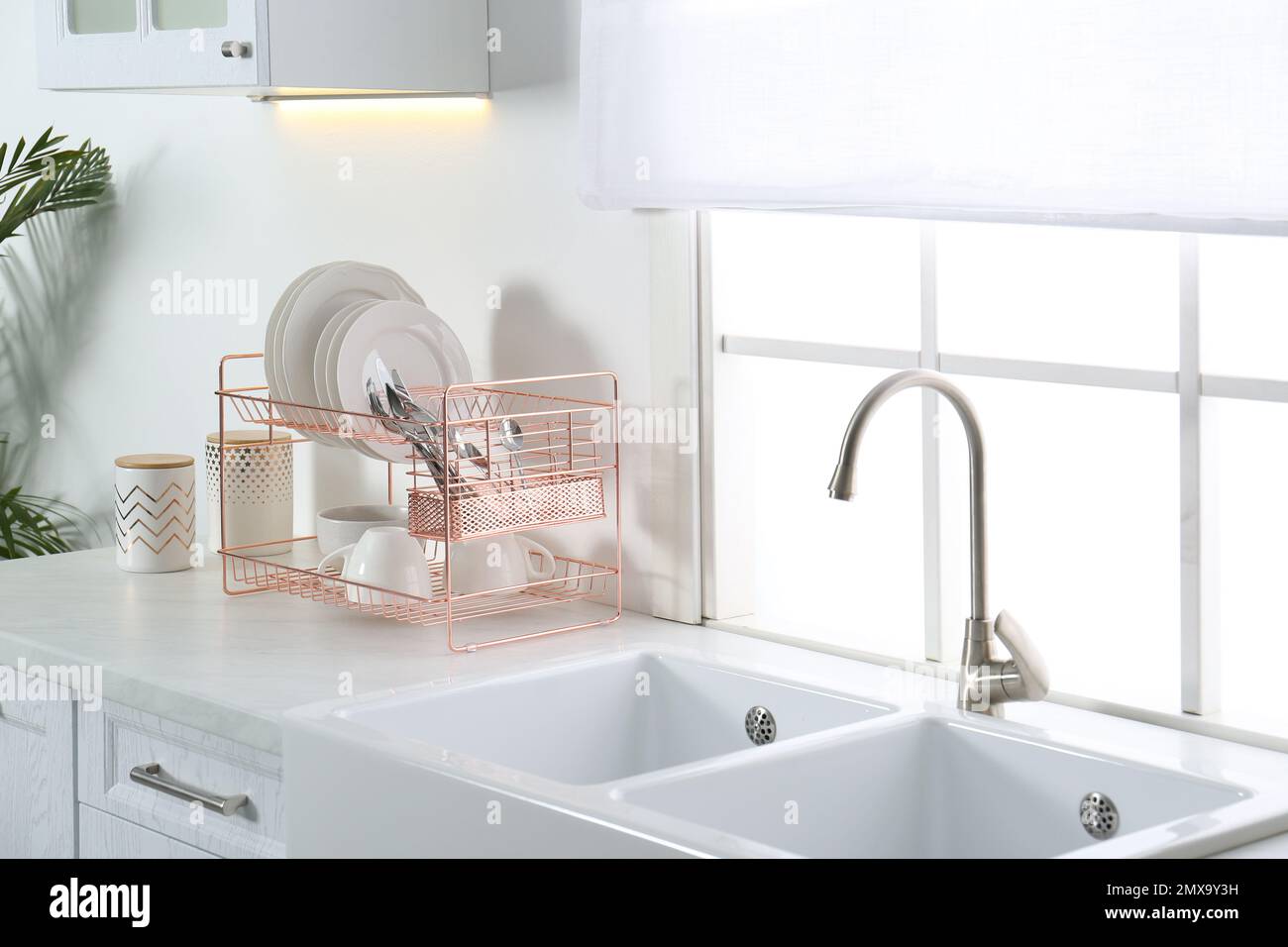 Griglia di asciugatura con piatti puliti sopra il lavandino in cucina