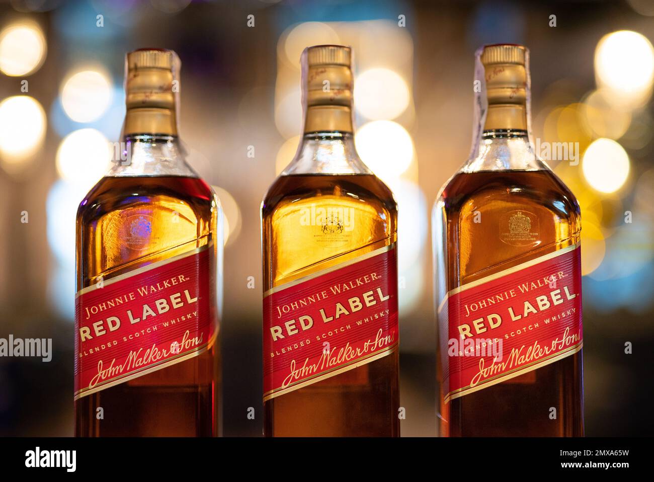 LVIV, UCRAINA - 3 SETTEMBRE 2022: johnnie Walker etichetta rossa tre bottiglie di vetro sul banco bar con bella bokeh e luce sullo sfondo Foto Stock