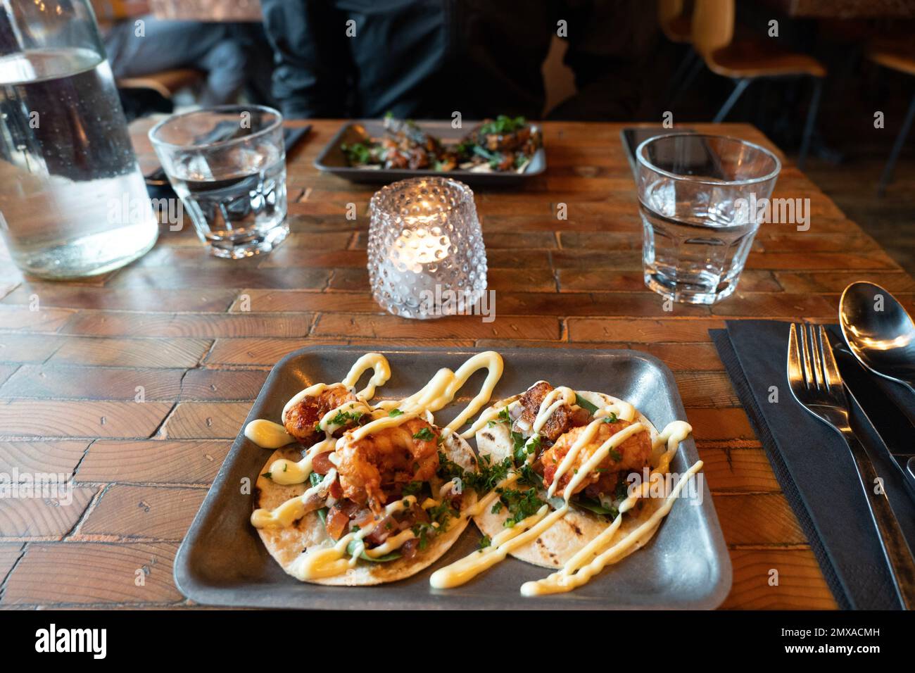 gusterete un pasto in un ristorante con tacos serviti su un tavolo di legno Foto Stock