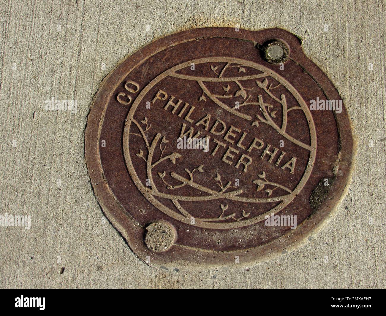 Un metro della Philadelphia Water Company copre un marciapiede in cemento. Foto Stock