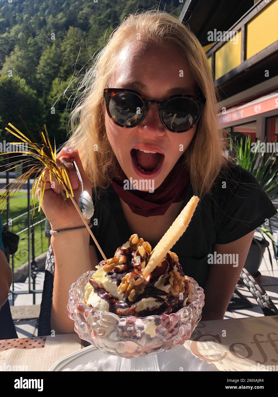 Giovane donna che mangia con entusiasmo un gelato di Sundae, Tirolo, Austria Foto Stock