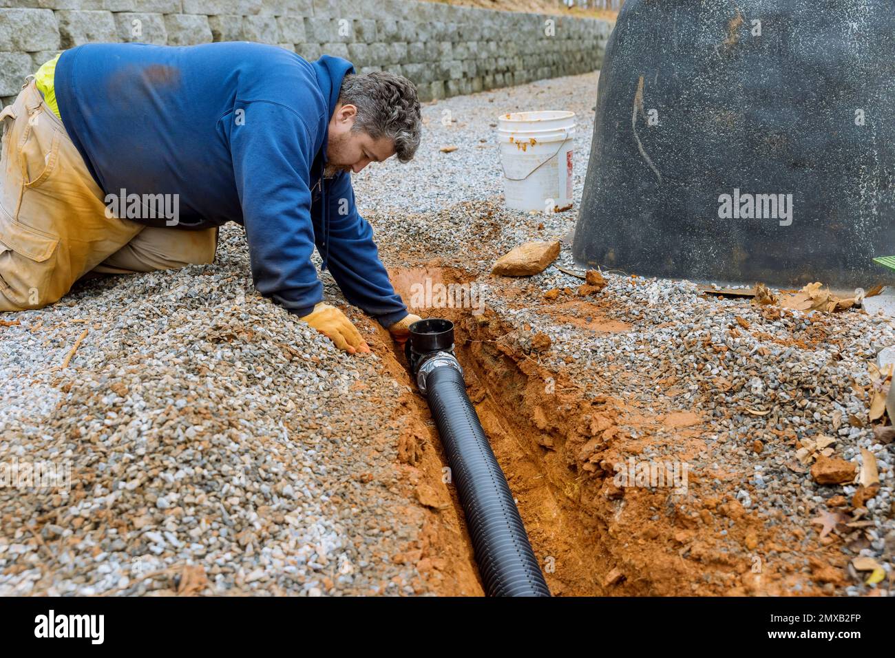 Montaggio del tubo di drenaggio dell'acqua piovana che verrà utilizzato per  la raccolta dell'acqua piovana in un parcheggio coperto con vialetto di  accesso in ghiaia Foto stock - Alamy