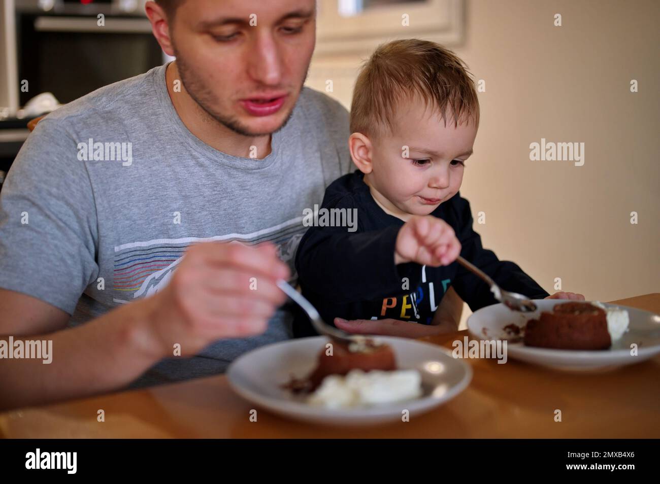 Padre e il suo bambino mangiano torta al cioccolato Foto Stock