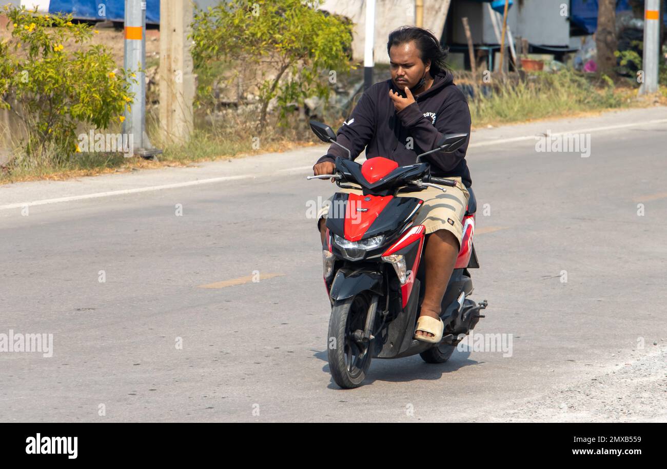SAMUT PRAKAN, THAILANDIA, 01 2023 FEBBRAIO, Un uomo cavalca una moto sulla strada di campagna Foto Stock