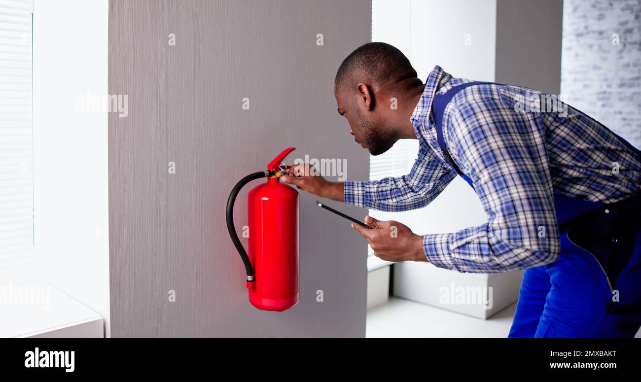 Professionista maschio che verifica Un estintore. Ispezione di sicurezza Foto Stock