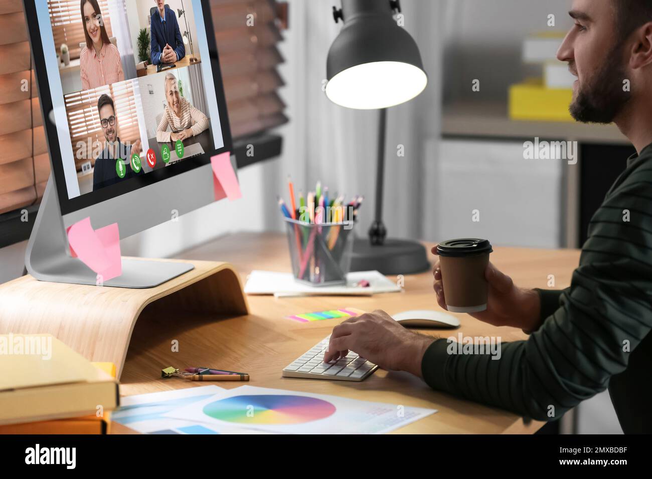 Uomo che ha una chat video con i colleghi al tavolo in ufficio. Lavoro di squadra Foto Stock