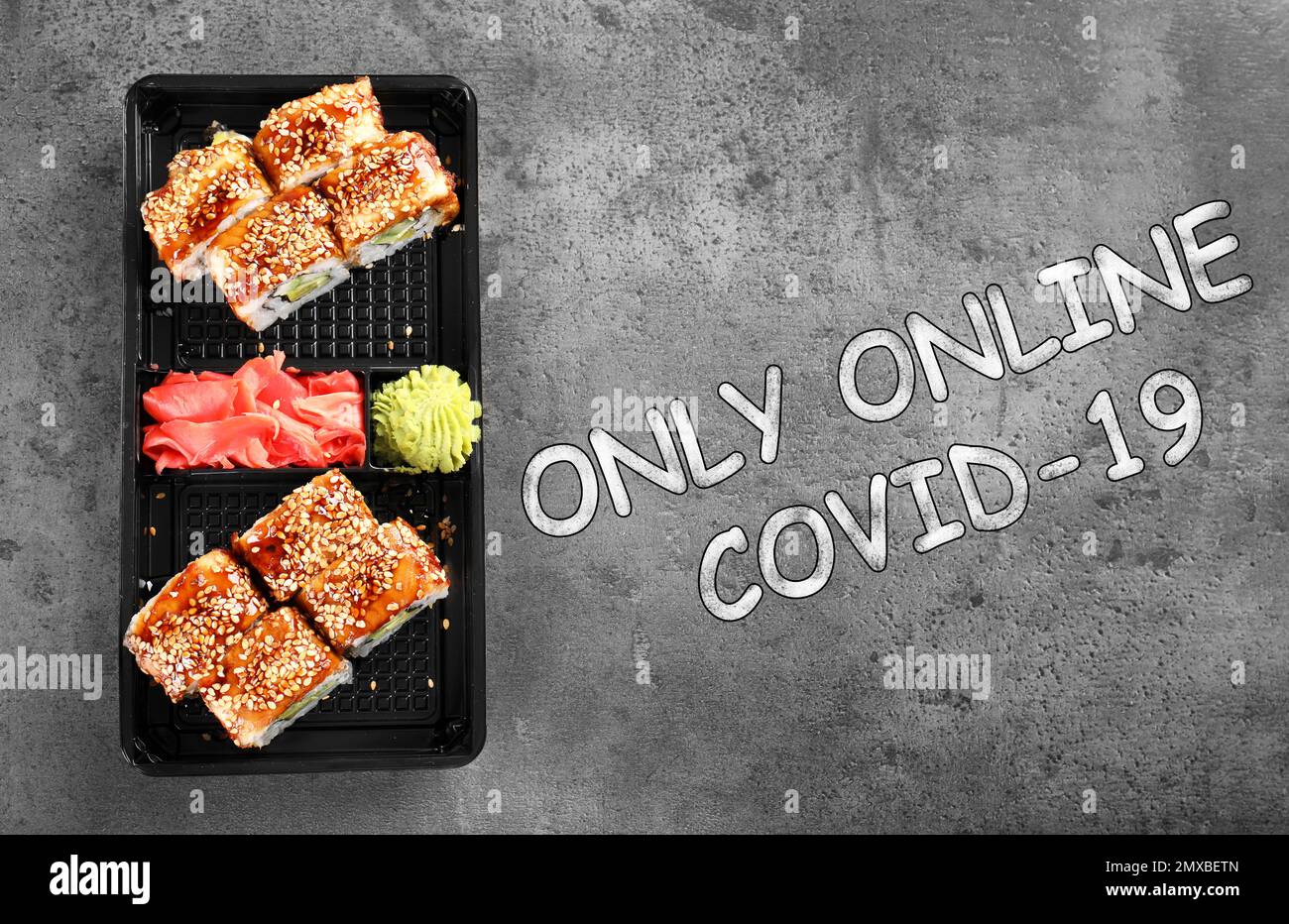 Gustosi panini sushi in scatola sul tavolo grigio, vista dall'alto. Servizio di consegna online di cibo Foto Stock