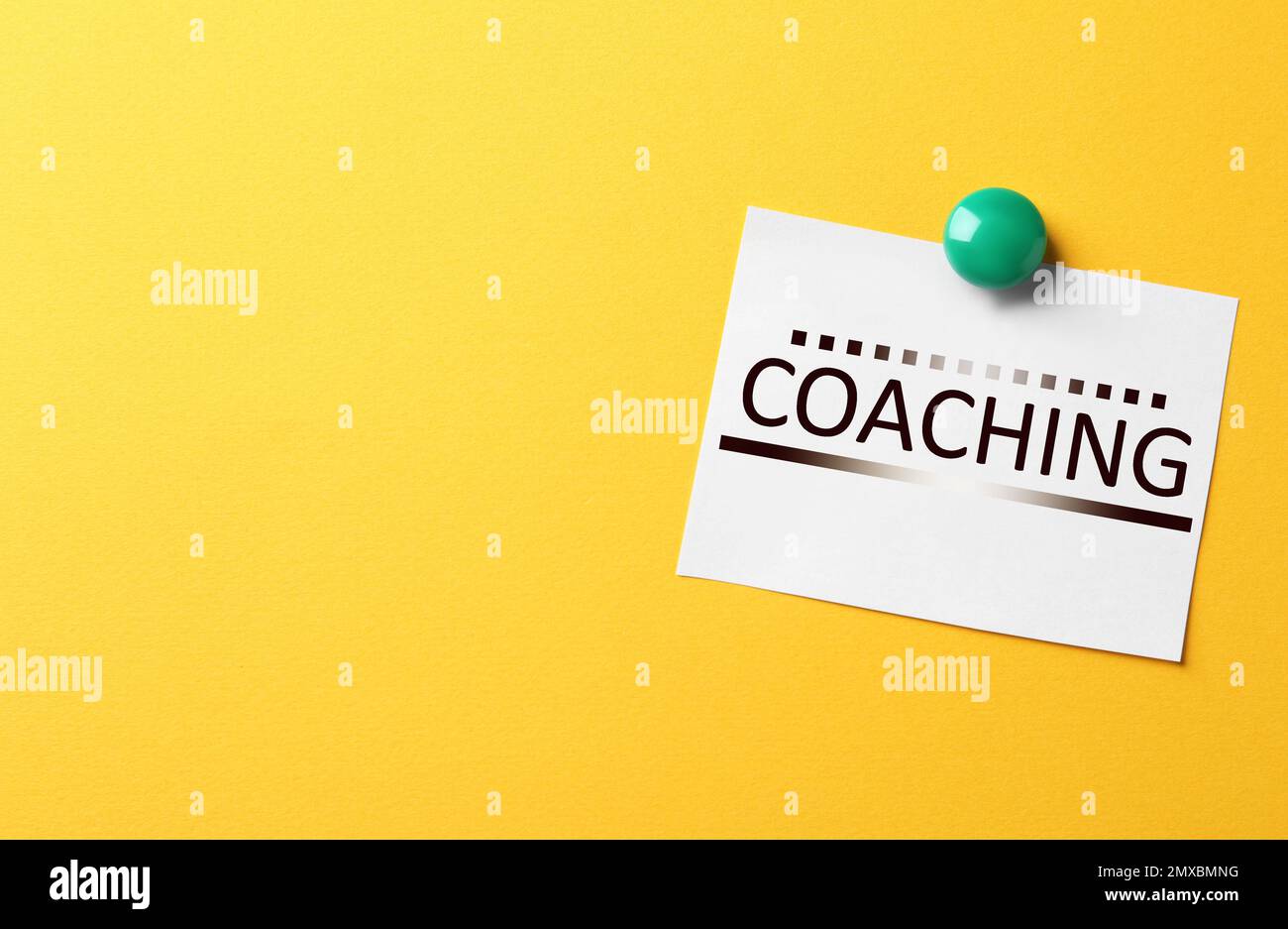 Apprendimento per adulti. Nota cartacea con parola COACHING su sfondo giallo, spazio per il testo Foto Stock