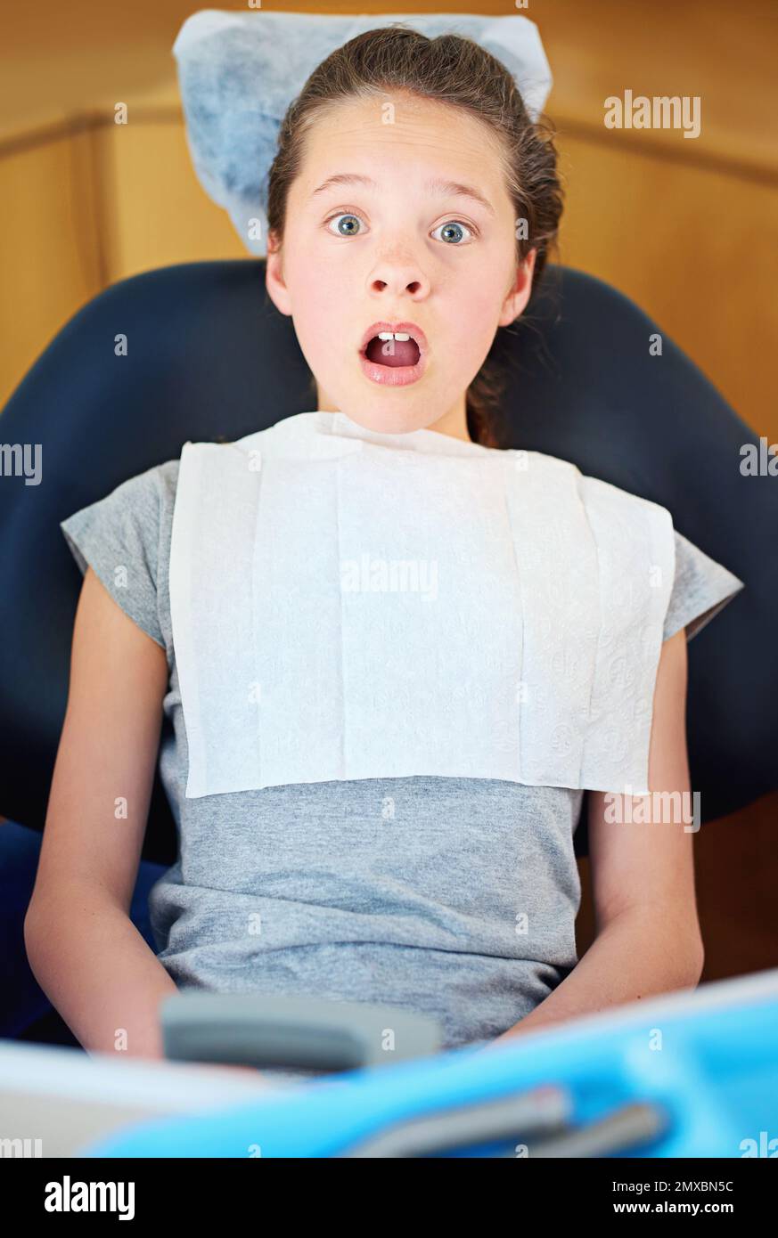 Nella temuta sedia dei dentisti... una giovane ragazza che guarda terrorizzata mentre si siede in una sedia dei dentisti. Foto Stock