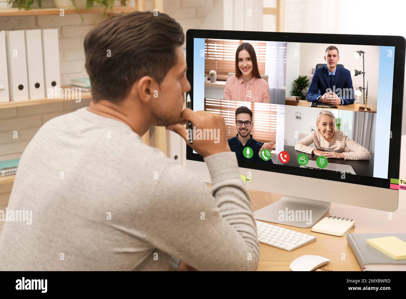 Uomo che ha una chat video con i colleghi al tavolo in ufficio. Lavoro di squadra Foto Stock