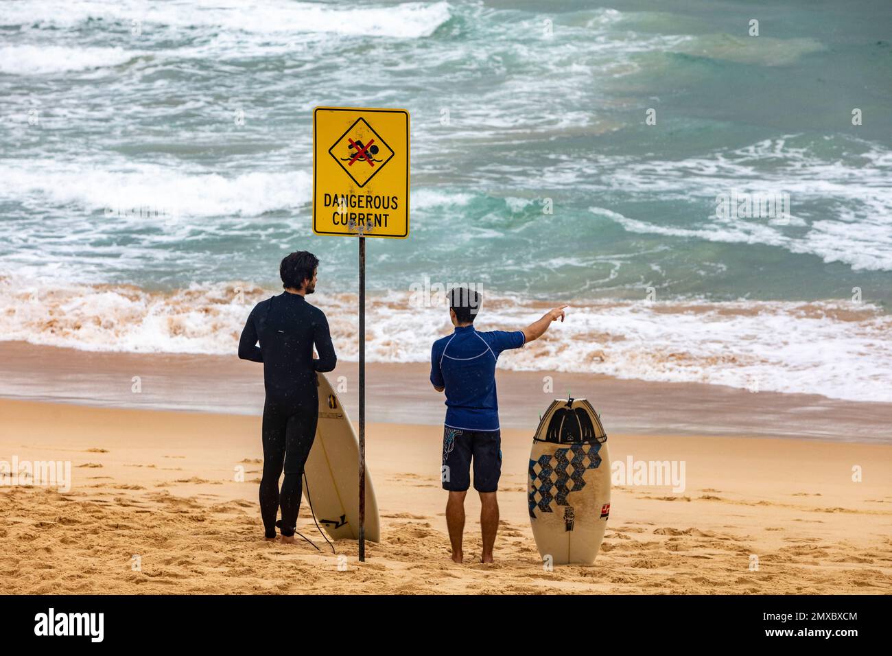 Due surfisti maschi si trovavano accanto al pericoloso cartello della corrente su una spiaggia di Sydney, Australia, che teneva surf e bodyboard Foto Stock