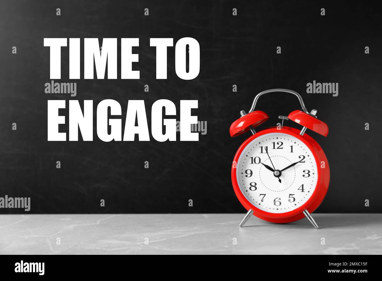 Texte sur time to Engage on blackboard near Alarm clock. (Tempo di inserimento nella lavagna vicino Foto Stock