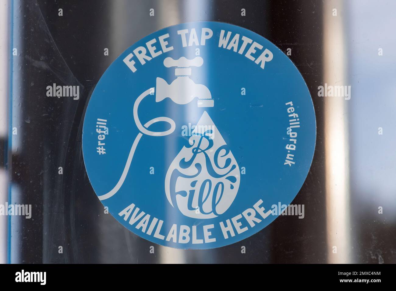 Acqua del rubinetto gratuita disponibile qui, refill.org.uk adesivo nella finestra del caffè, Inghilterra, Regno Unito. Per riempire le bottiglie d'acqua e ridurre l'uso di plastica monouso Foto Stock