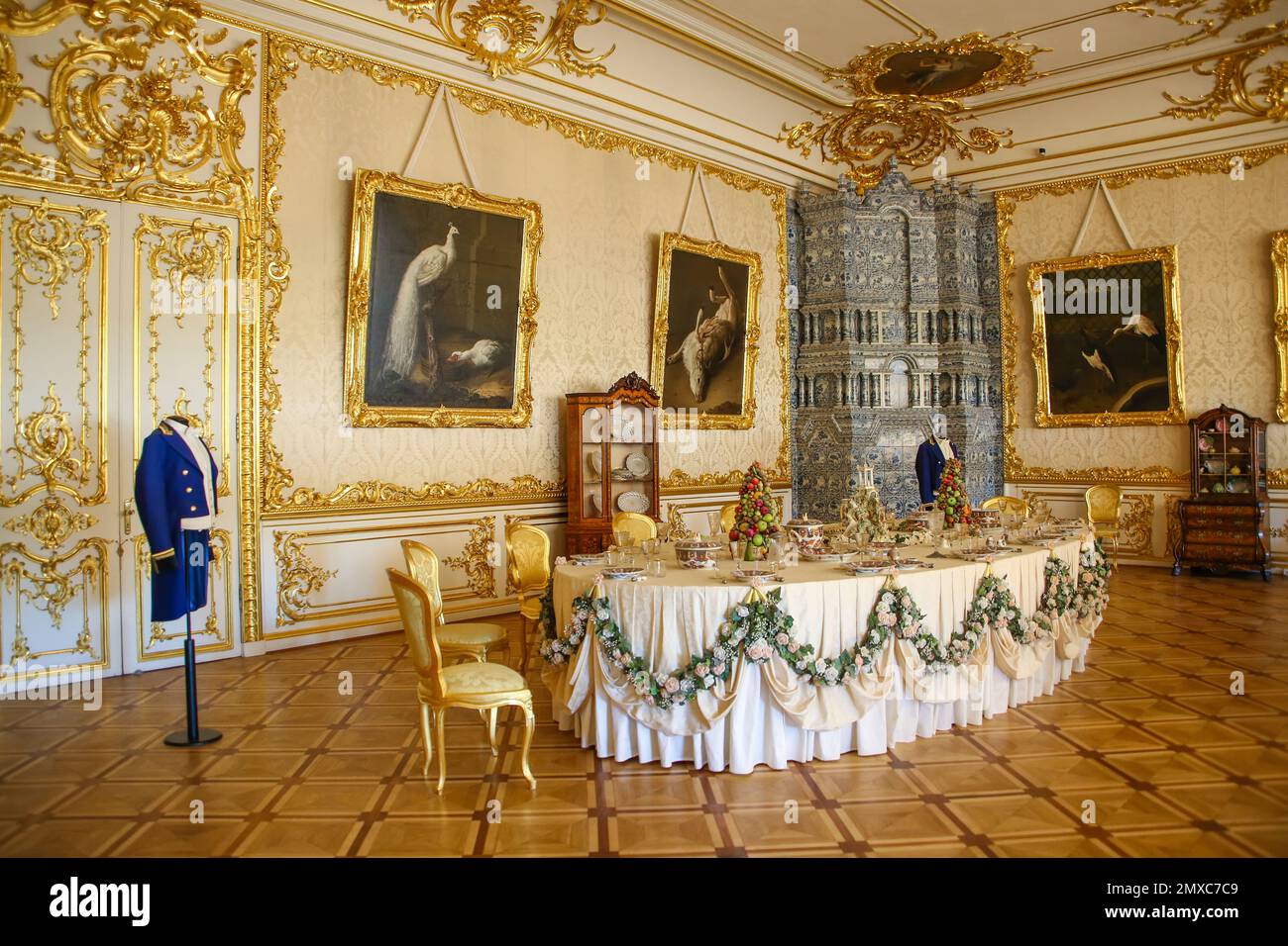 White Dining Room, Catherines Palace, Tsarskoye Selo, Russia. Pareti bianche con ornamento dorato, con scaldabagno in ceramica blu e bianca. Foto Stock