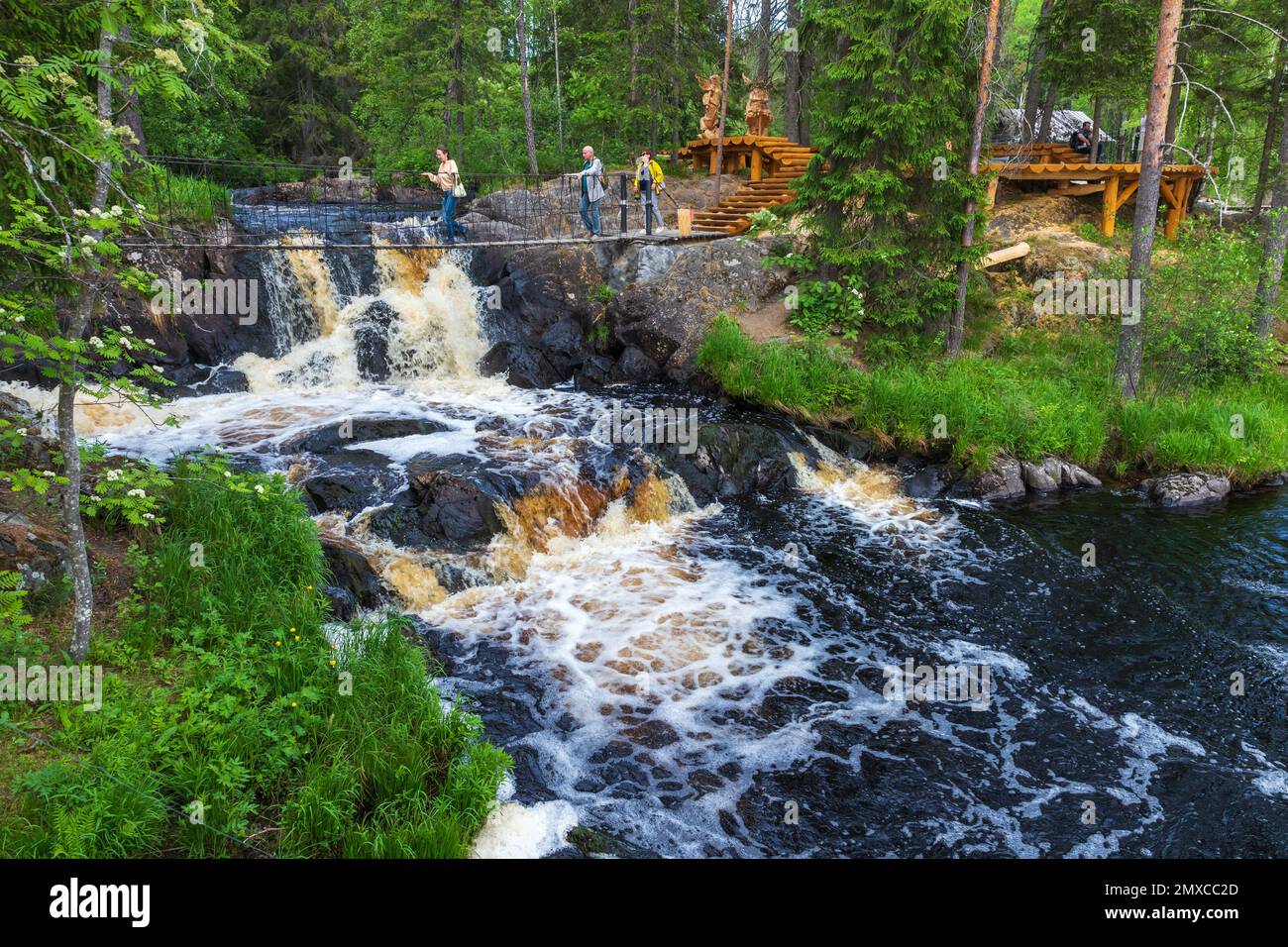 Ruskeala, Russia - 11 giugno 2021: I turisti camminano il ponte sospeso sulle cascate naturali di Ruskeala in un giorno estivo Foto Stock