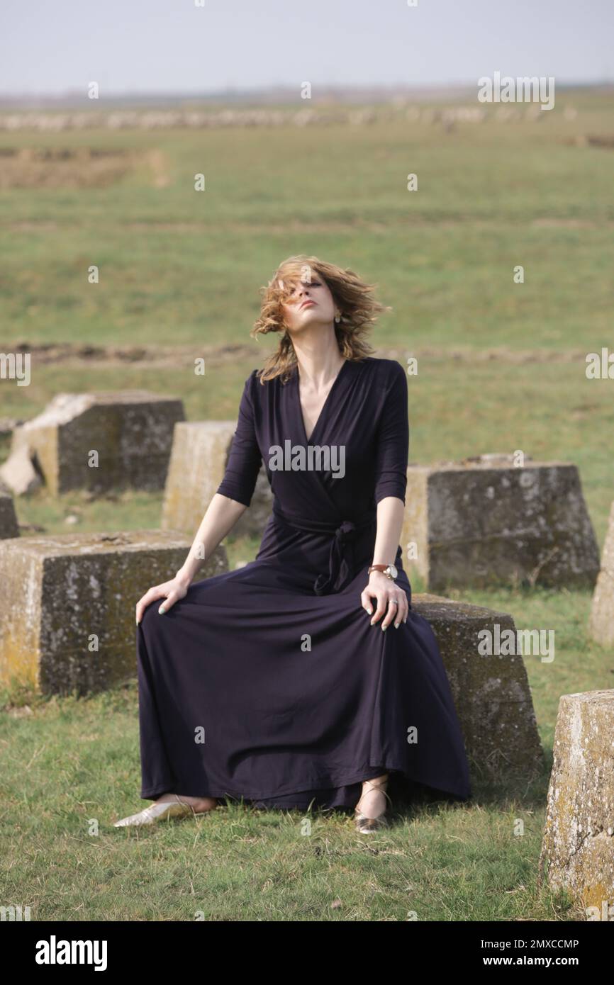 Ritratto moda outdoor di modello femminile in abito nero maniche lunghe maxi ritratto moda outdoor di modello femminile in abito nero maniche lunghe maxi Foto Stock