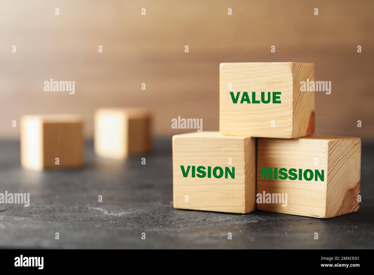 Cubi di legno con parole VALORE, VISIONE e MISSIONE su tavola di pietra grigia, closeup Foto Stock