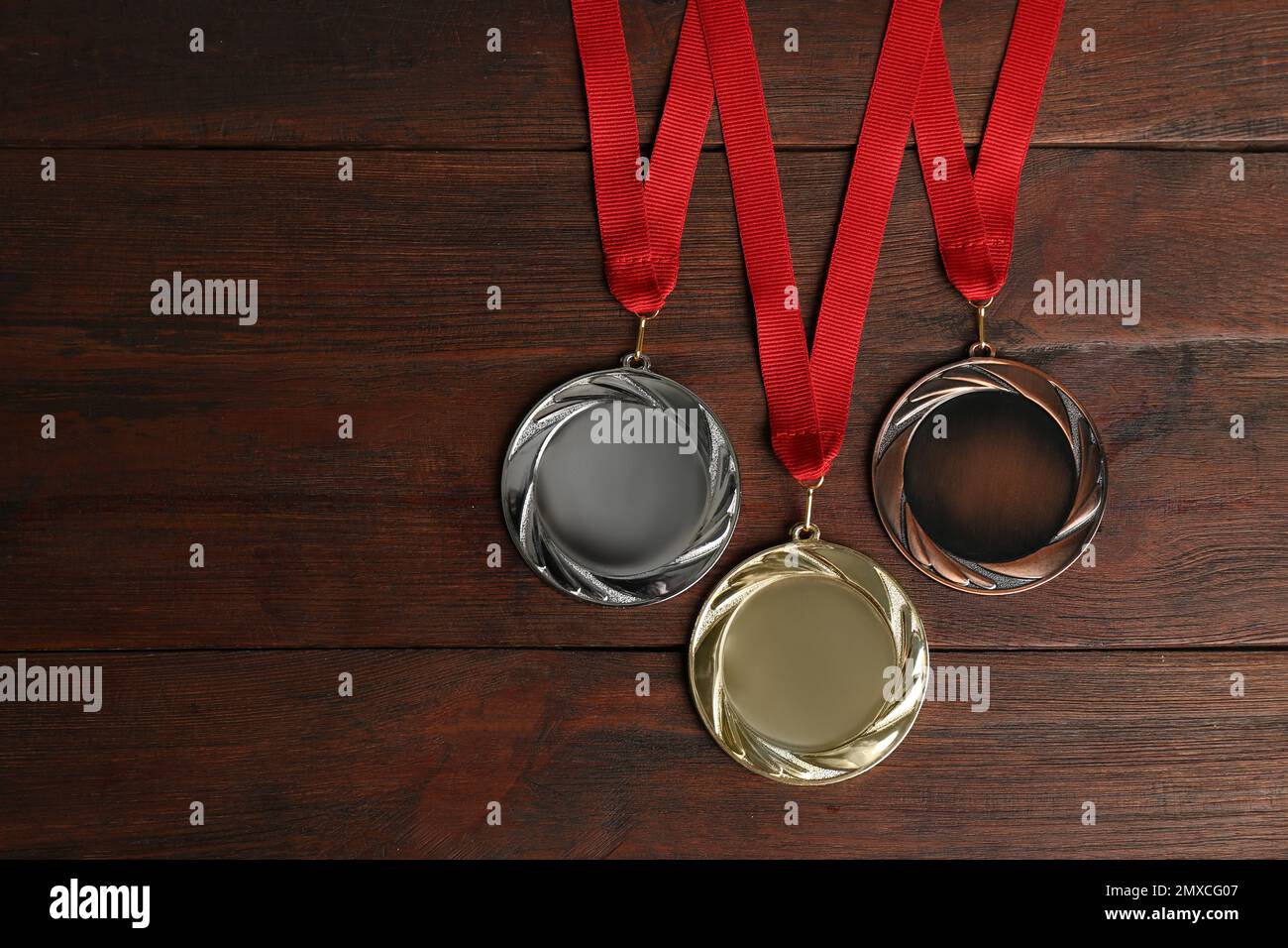 Medaglie d'oro, d'argento e di bronzo su sfondo ligneo, giacitura piatta. Spazio per il design Foto Stock