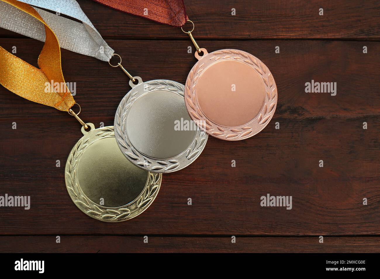 Medaglie d'oro, d'argento e di bronzo su sfondo ligneo, giacitura piatta. Spazio per il design Foto Stock