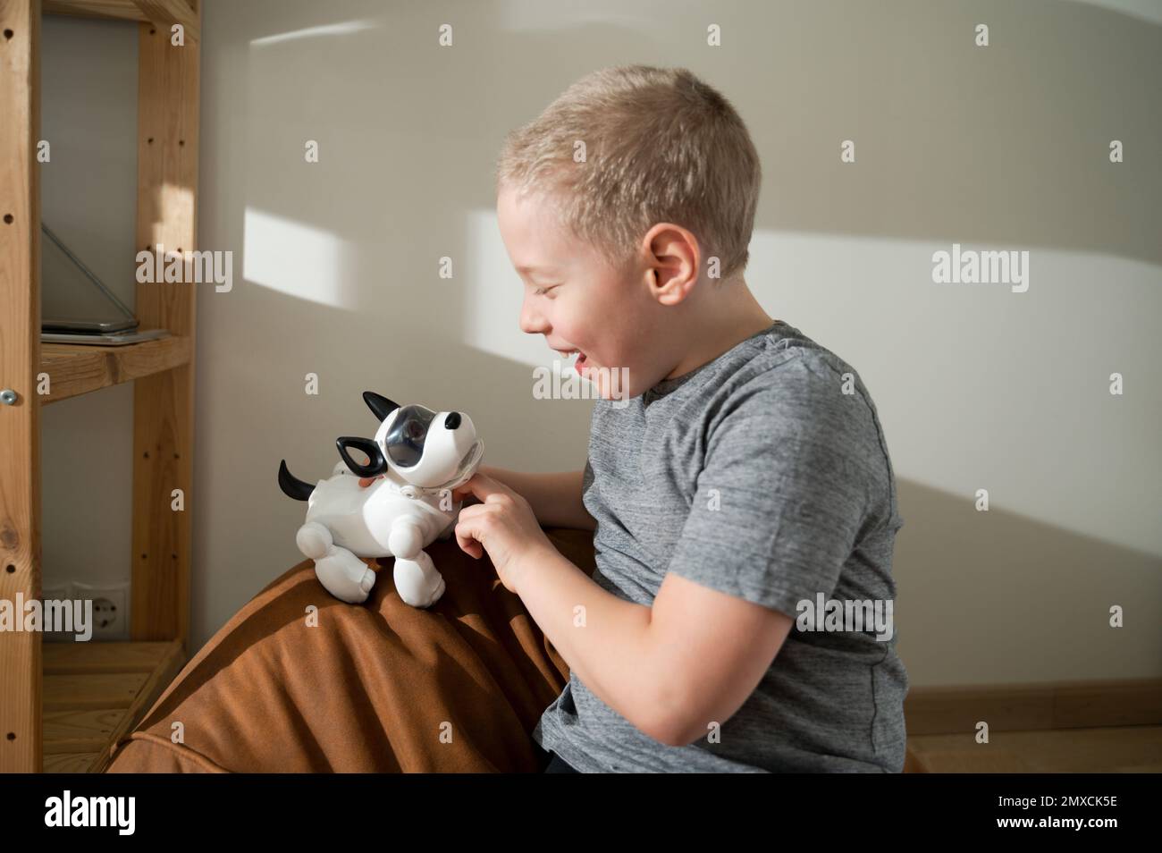 Ragazzo che gioca con un cane robotico, ridendo, solletico Foto Stock