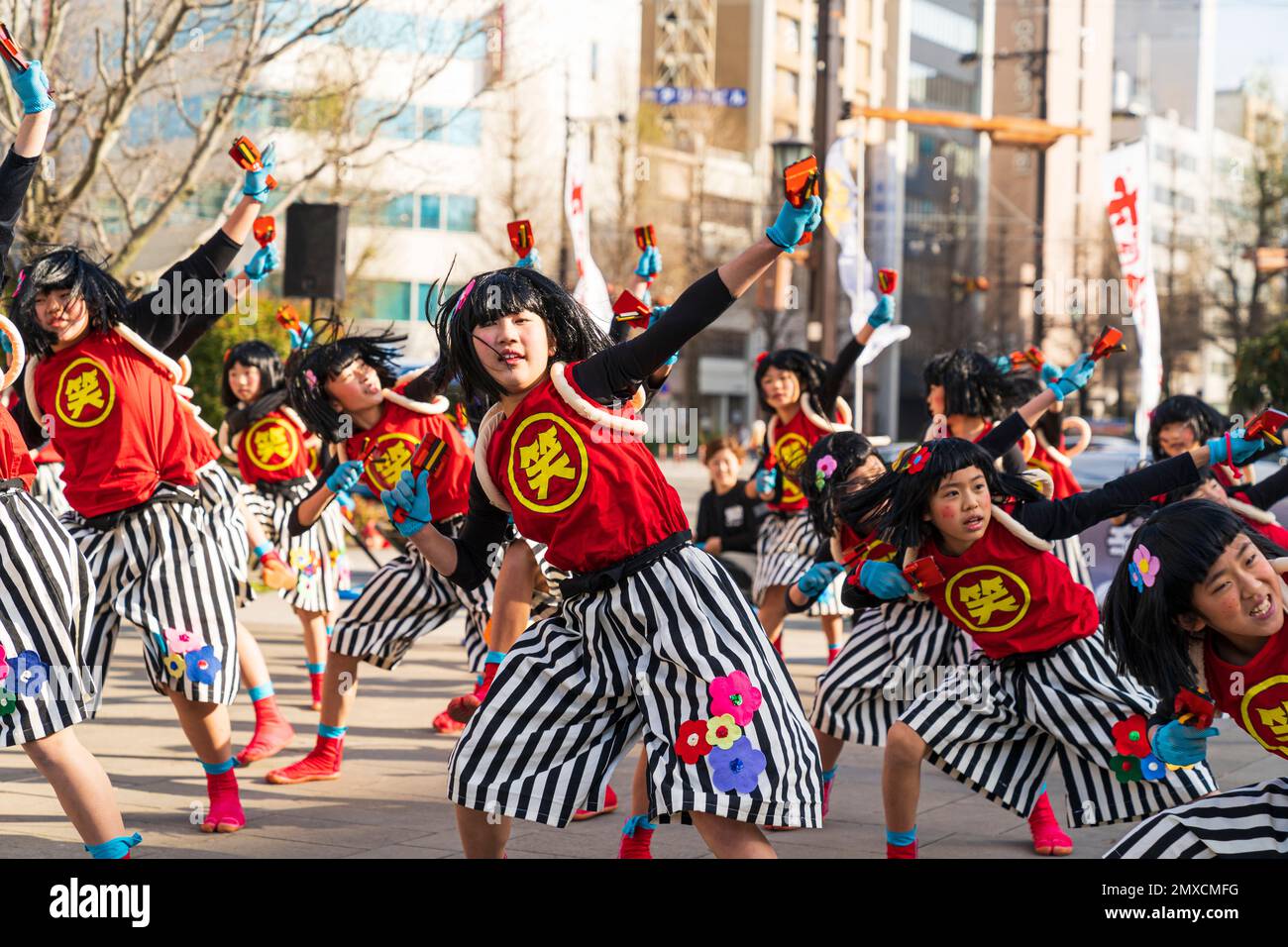 Squadra giapponese di danzatrici Yosakoi bambina che ballano e tengono naruko, clapper, nella piazza della città in occasione dell'annuale festival Kyusyu Gassai a Kumamoto. Foto Stock